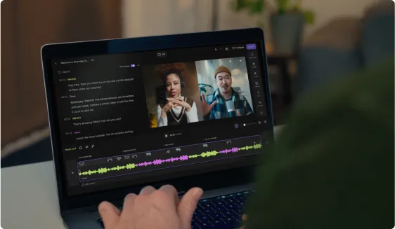 Person using laptop with video call showing two people and an audio editing timeline visible on screen.